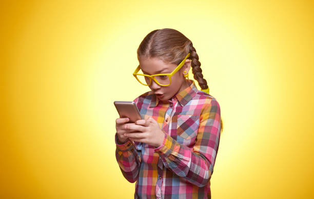 Beautiful teen girl is surprised playing with the phone stock photo
