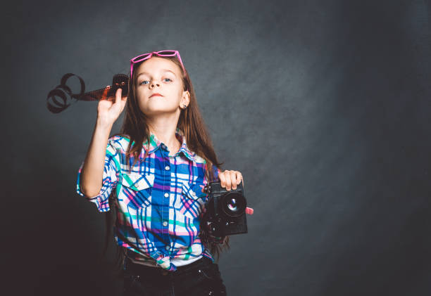 little beautiful girl with an old camera. young photographer - photographer enjoyment elegance old fashioned imagens e fotografias de stock