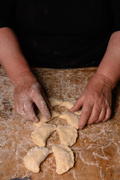 istock An old lady makes dumplings in a row on a table on a dark background 1094859440