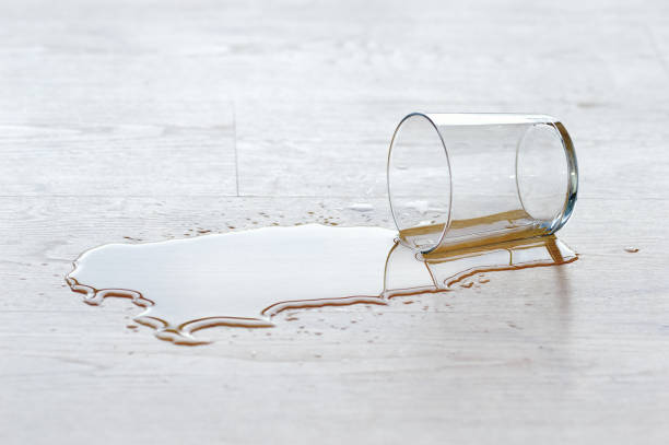 drinking glass fallen to the ground water drinking glass falling over the wood laminate flooring with a puddle of water spilling stock pictures, royalty-free photos & images