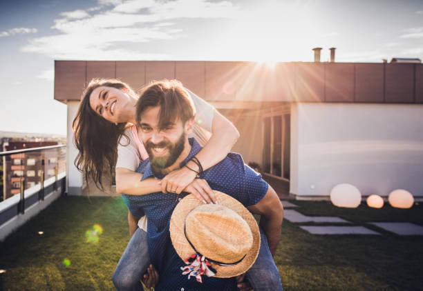 istock Young happy couple having fun while piggybacking on a penthouse terrace. 1094860250
