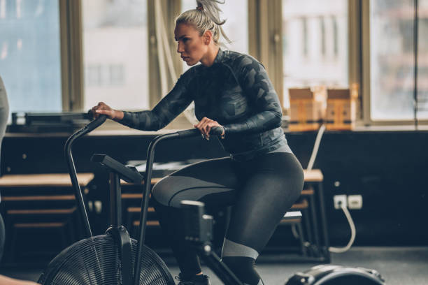 woman training on exercise bike in gym - spinning instructor exercising gym imagens e fotografias de stock