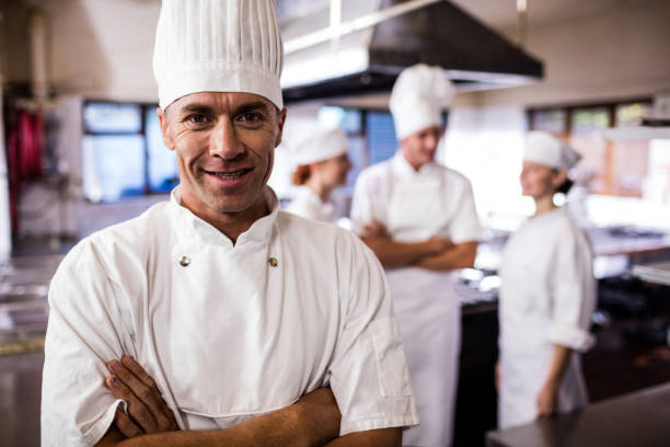 istock Male chef standing with arms crossed while coworker interacting with each other in kitchen 1094871972