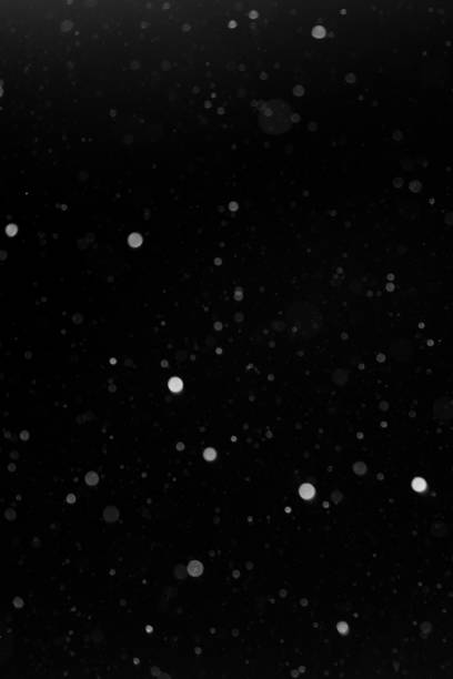 istock a bokeh of white snow on a black background 1094877768