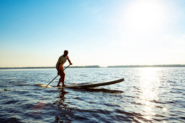 istock Joyful  guy paddling on a SUP board 1094891652