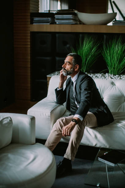 istock Middle-aged businessman using mobile phone in modern office on sofa 1094897230