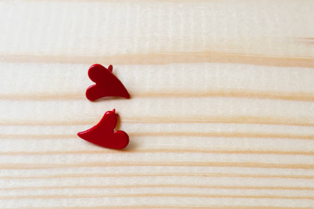 Two metallic red hearts on a wooden background