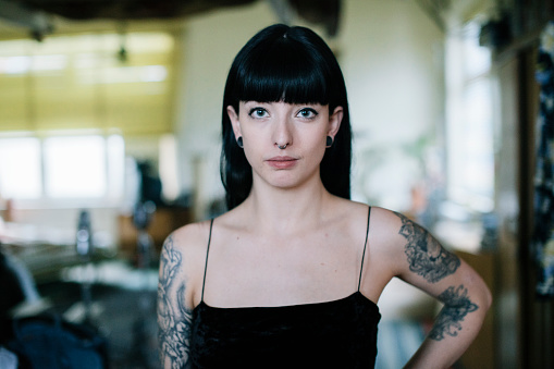 Portrait of tattooed woman standing in her apartment.
