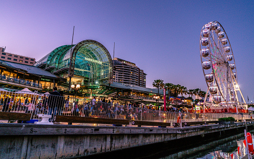 23rd December 2018, Sydney Australia: Harbourside shopping centre view at dusk in Darling Harbour with Ferris wheel and people in Sydney NSW Australia