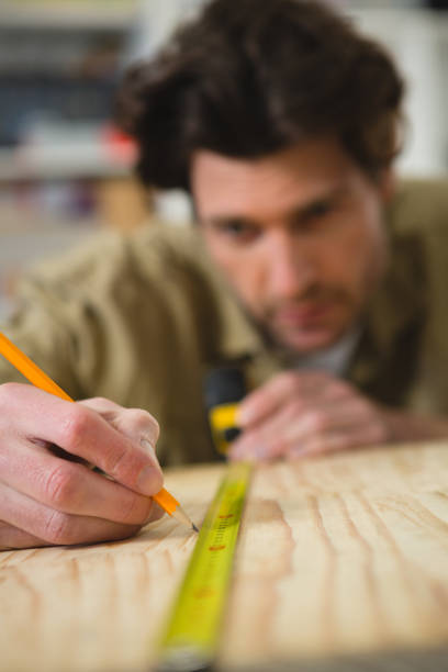 istock Male carpenter measuring and marking wood 1094905962