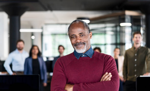 istock Confident mature businessman against colleagues 1094909912