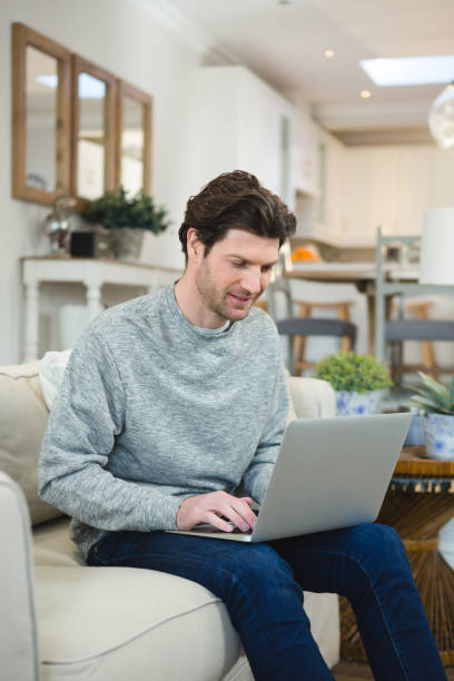 istock Man using laptop in living room 1094909946