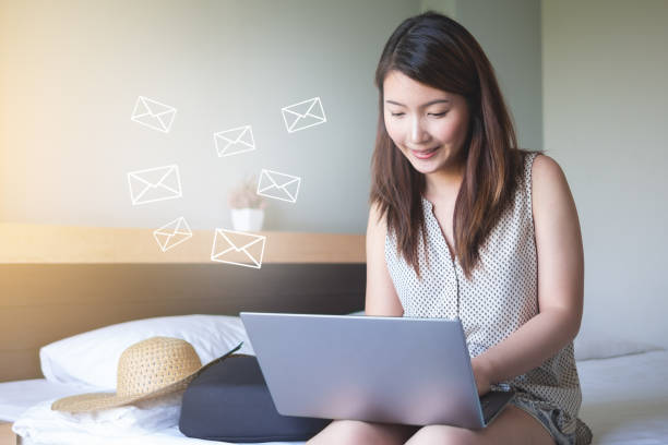 午前中に電子メールを送信するラップトップを使用してベッドの上に座っている女性 - connection e mail typing human hand ストックフォトと画像