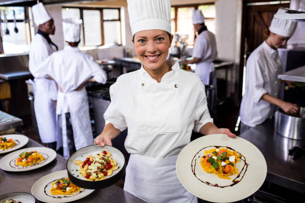 istock Female chef holding plate of prepared pasta in kitchen 1094918430