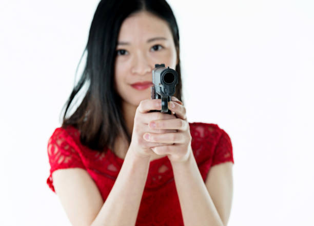 Beautiful woman holding a gun on white background.