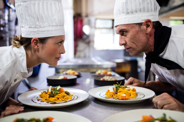 Male and female chefs looking at each other in kitchen at hotel
