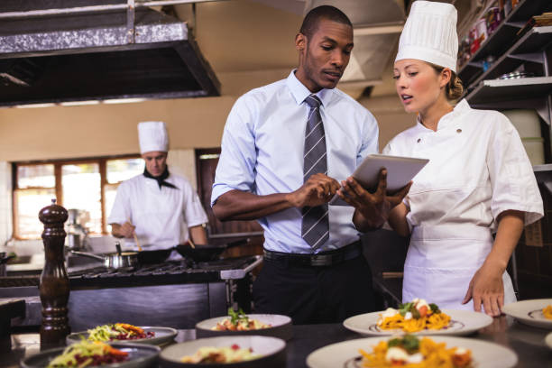남성 관리자와 여성 요리사 부엌에 디지털 태블릿을 사용 하 여 - 호텔 뉴스 사진 이미지