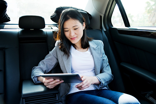 Businesswoman using digital tablet in car.