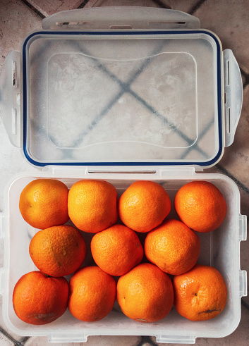 tightly packed fruits (clementines) in a plastic food container