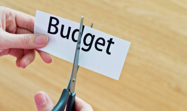 istock Human hand cutting the budget word 1094922230