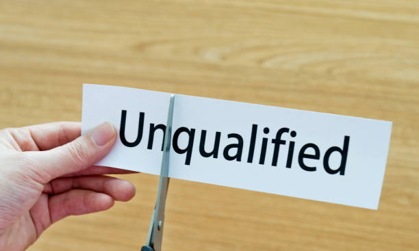 istock Human hand cutting word on paper unqualified become qualified 1094922338
