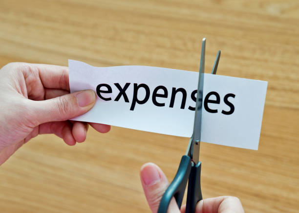 istock Human hand cutting the expenses word 1094922448
