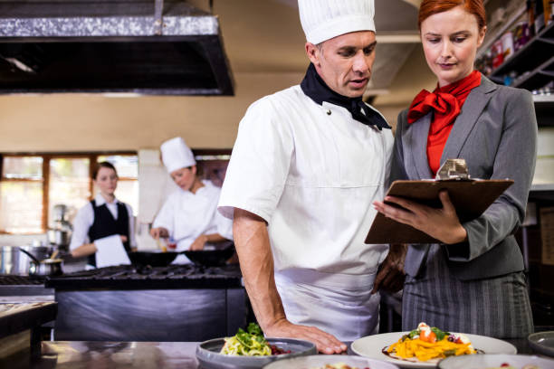 istock Female manager and male chef writing on clipboard in kitchen 1094922836