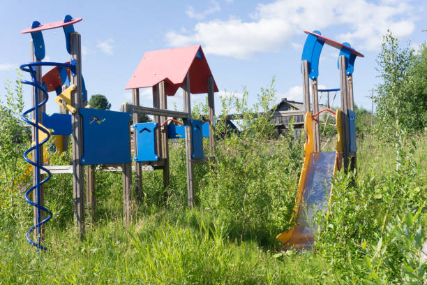 old neglected playground equipment, overgrown with weeds. - swing playground empty abandoned imagens e fotografias de stock