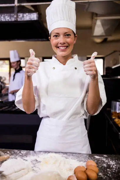 Photo of Female chef showing thumbs up in kitchen