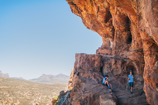 Two Young Adventurous Caucasian Boys in a Sandstone cave at Truitjieskraal in the Cederberg Wilderness Area with Sneeuberg landscape in the background South Africa