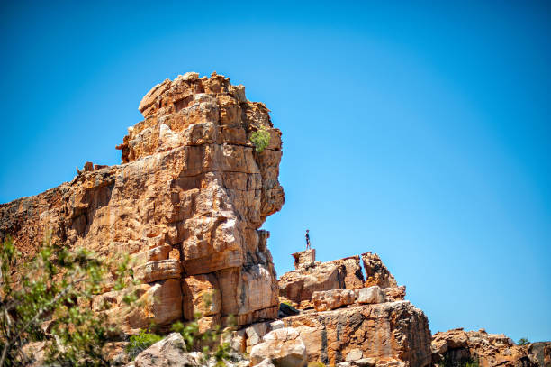 Man looking out from distant rock An active Caucasian male standing on a distant high up rock looking out taken from a distance at Truitjieskraal Cederberg South Africa cederberg mountains photos stock pictures, royalty-free photos & images