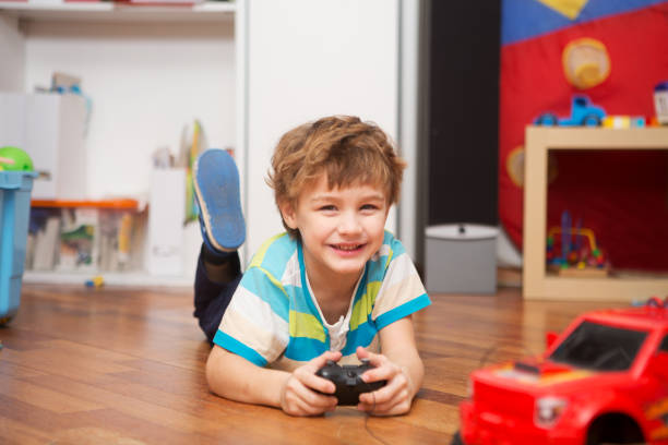 a boy playing with radio-controlled car at home. stock photo