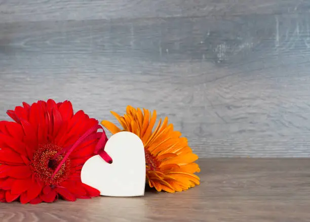 big red and orange flowers with heart shape on rustic wooden background