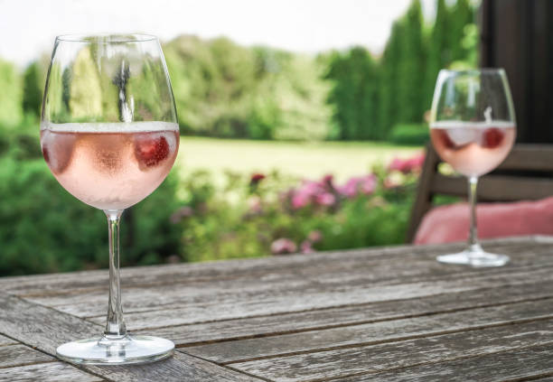 rose wein gläser auf einem holztisch im garten - roséwein stock-fotos und bilder