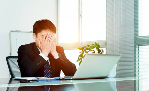 istock Tired businessman covering face at desk 1094936864