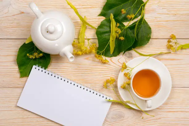 linden herbal tea with empty notepad on wooden table