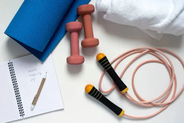 jump rope, yoga mat, dumbbells, white bath towel, notepad, close-up on a white background
