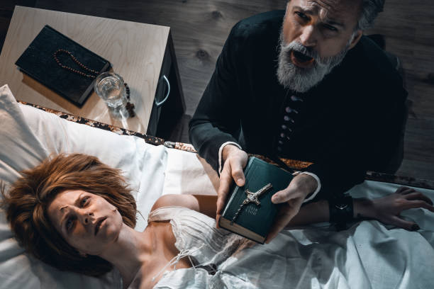 Old priest performing exorcism ritual of young possesed woman Old priest performing traditional exorcism ritual of young possesed woman in dark hospital room exorcism stock pictures, royalty-free photos & images