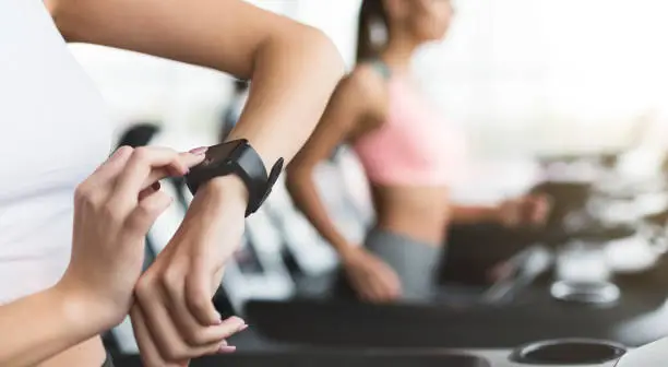 Sportswoman looking at smartwatch with blank screen at gym, crop, copy space