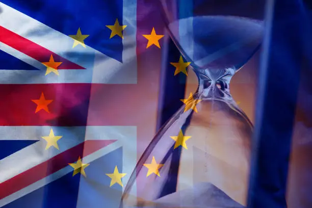 Closeup elegant sandglass counting down time to Brexit on background of overlapped flags of Great Britain and European Union