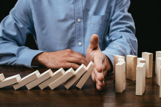 istock partial view of man preventing wooden blocks from falling on desk 1094978664