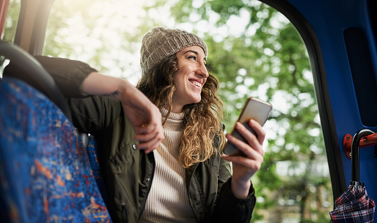 Shot of a young woman using a mobile phone while traveling on a bus