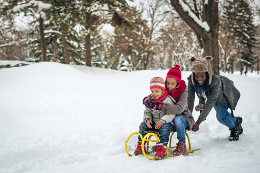 Children ride on snow plate and having fun. Outdoor play. Cold temperature. Winter time.