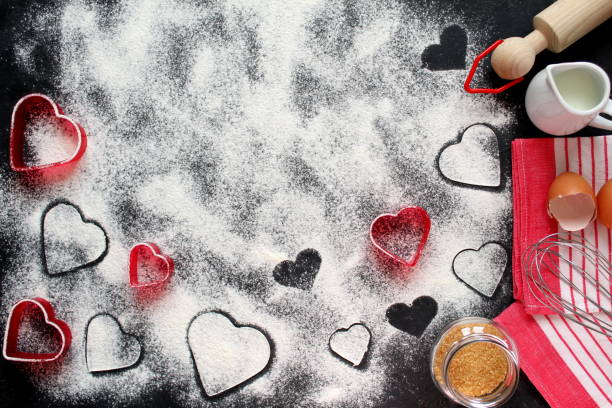 istock Baking background with flour, rolling pin, eggs, milk, sugar cane and heart shape on dark background. 1094982864