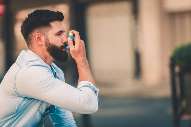 männer mit asthma-inhalator outdoor - asthmatisch stock-fotos und bilder