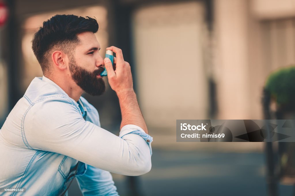 Men using asthma inhaler outdoor Asthmatic Stock Photo