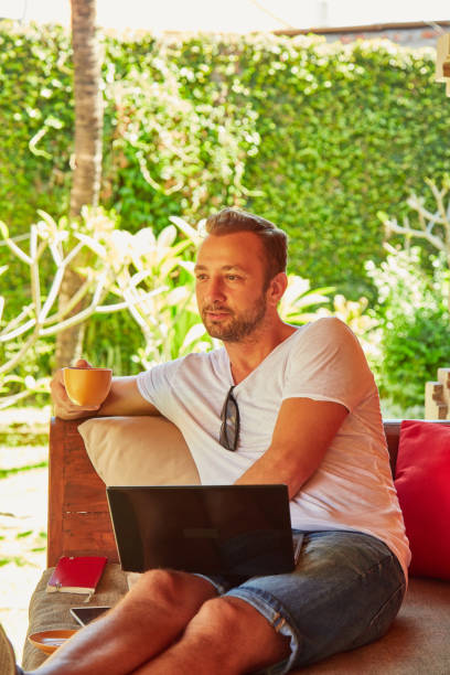 istock Man with coffee / tea and laptop on a home porch. 1094994920