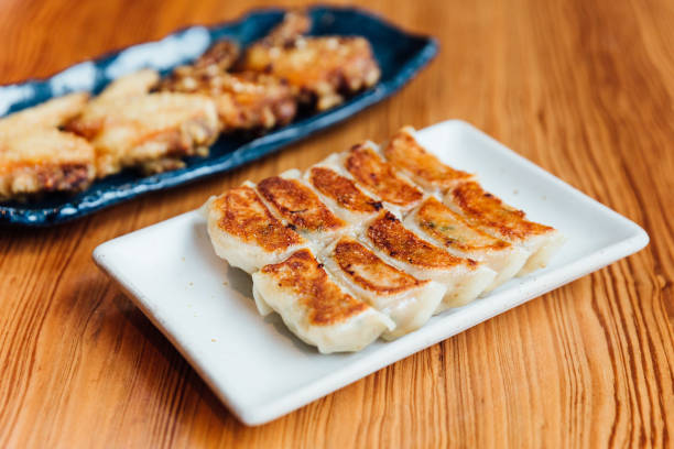 istock Yaki-Gyoza set (Japanese Pan-Fried Dumplings) served on white plate with fried chicken in background. 1095005784