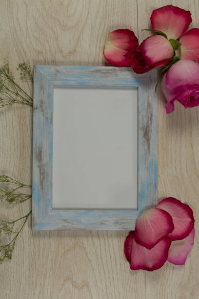 istock Empty photo frame with rose flower and petals 1095009352