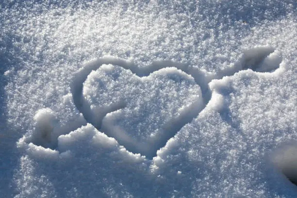 pierced heart drawn in the snow in the sun